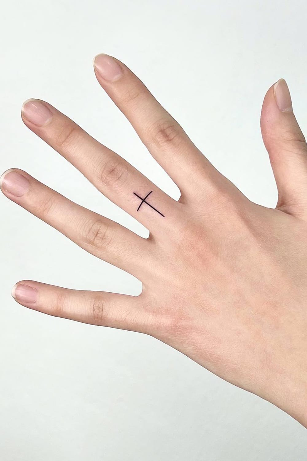 Small cross tattoo on finger