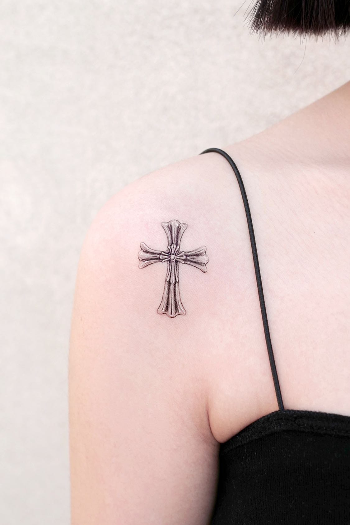 Small cross tattoo on shoulder